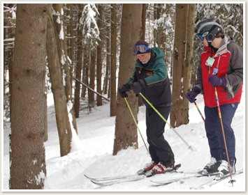 Teacher and student cross country skiing through woods in winter
